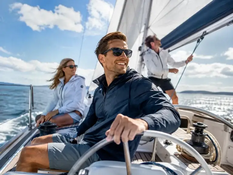 Groep zeilers geniet van een zonnige dag aan boord van een moderne zeilboot op open water.